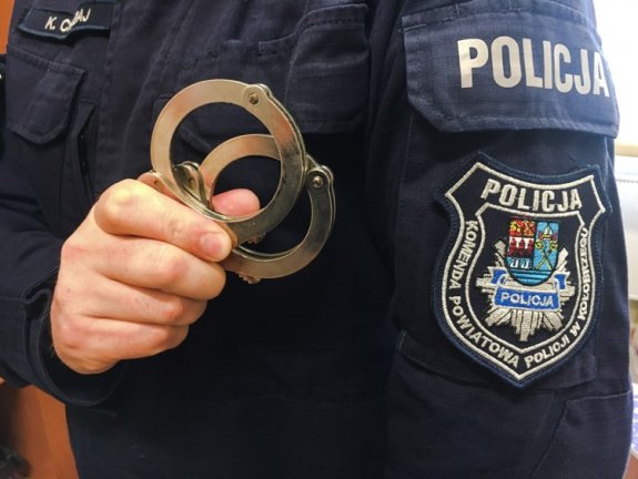 policjant trzyma kajdanki w ręku