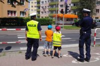 policjanci z dziećmi przy przejściu dla pieszych